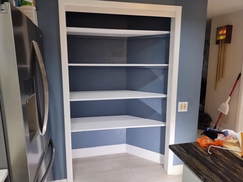 Kitchen pantry with white shelving, blue walls