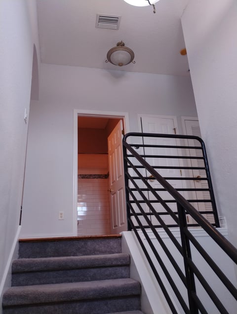 Stairwell with gray carpeted steps, black metal railing