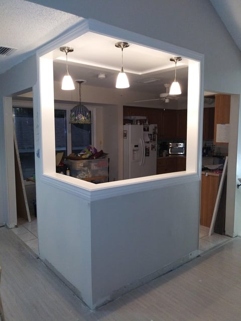 Modern kitchen with white island featuring pendant lighting and interior pass-through window overlooking appliances