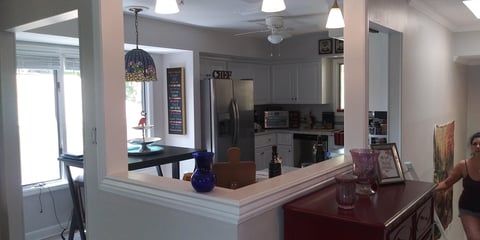 Modern open-concept kitchen with white cabinetry, dark countertop, stainless steel appliances, and bar seating overlooking the dining area
