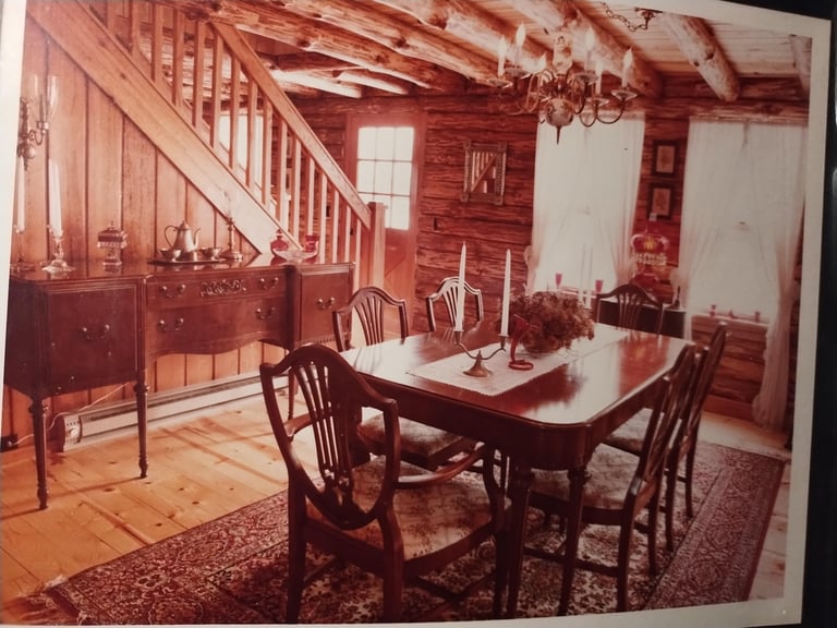 Interior of a colonial-style dining room with wooden furniture, a dining table with chairs, staircase, and red-tinted decor