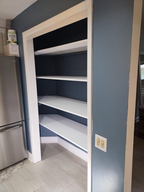 Kitchen pantry with white shelving and dark blue walls