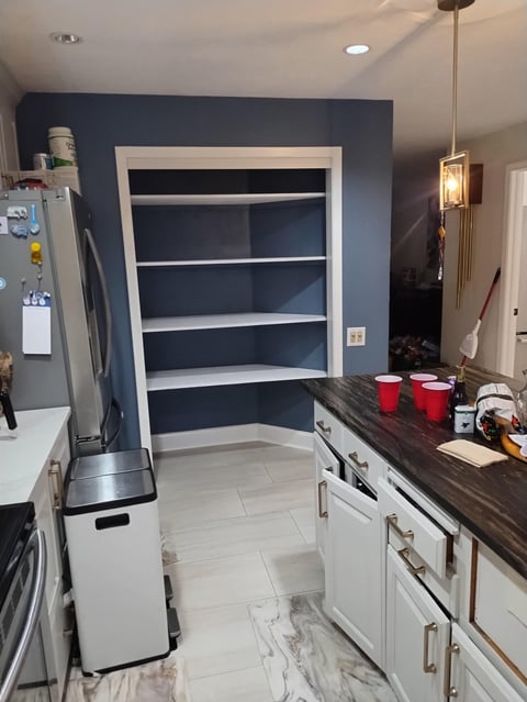 Kitchen pantry with white shelving against navy blue accent wall