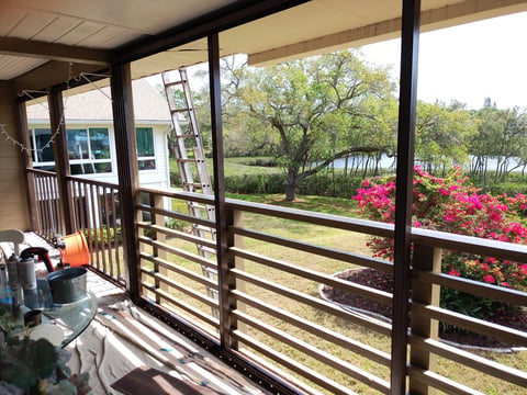 Covered porch with metal railings overlooking garden